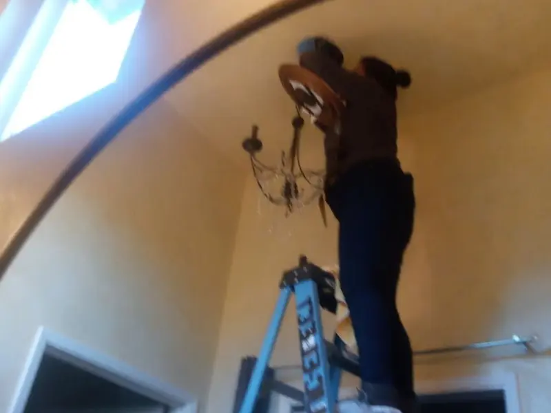 Electrician installing a chandelier in a Mayfield residence